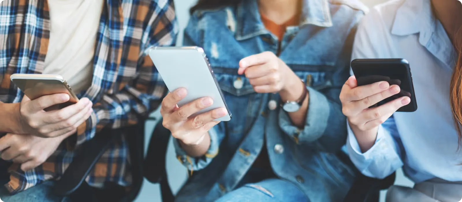 The hands of three communicating people who are holding smartphones
